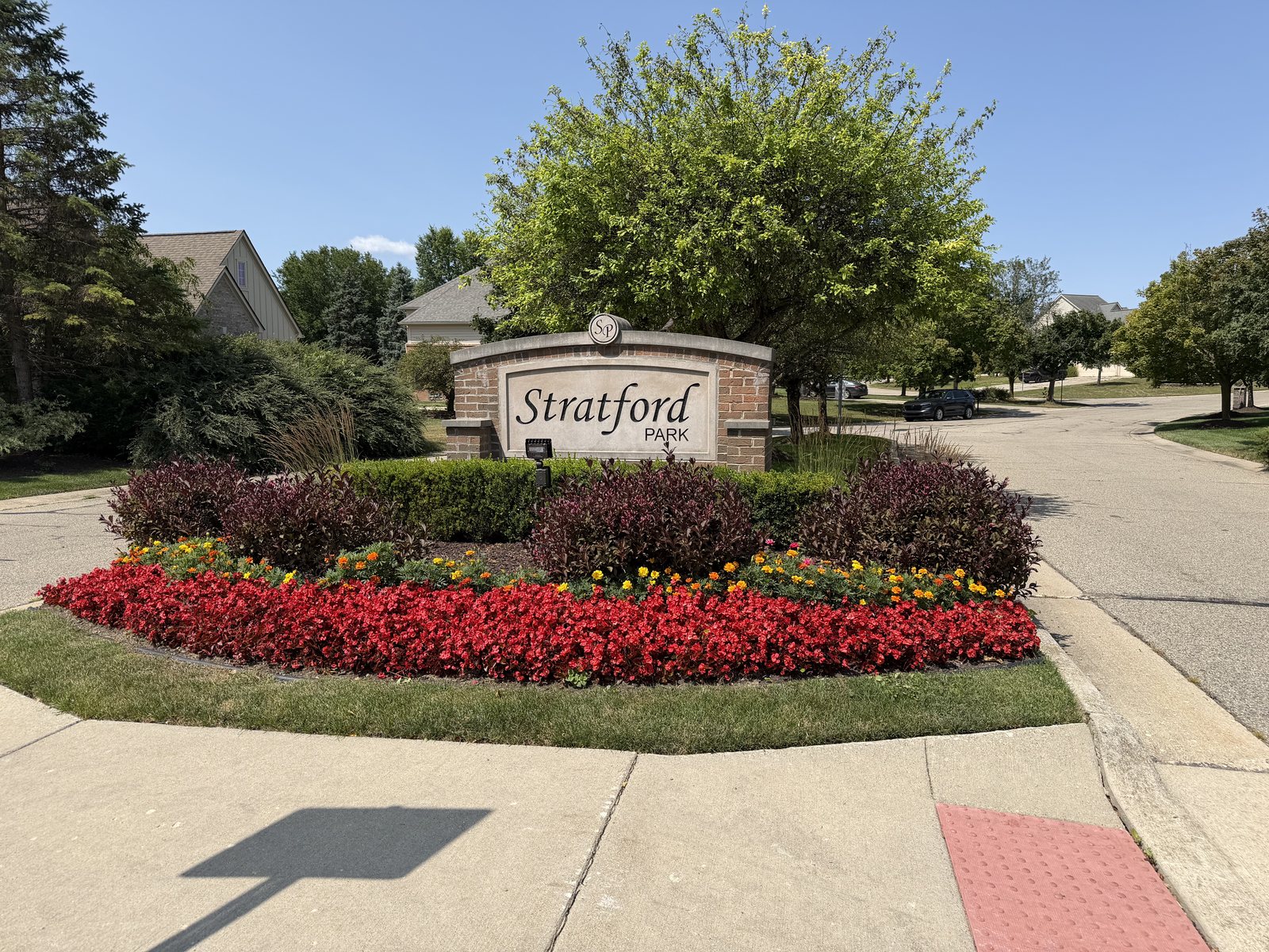 Brick entrance sign for the Stratford Park neighborhood in Canton, Michigan, with flower beds and homes beyond.