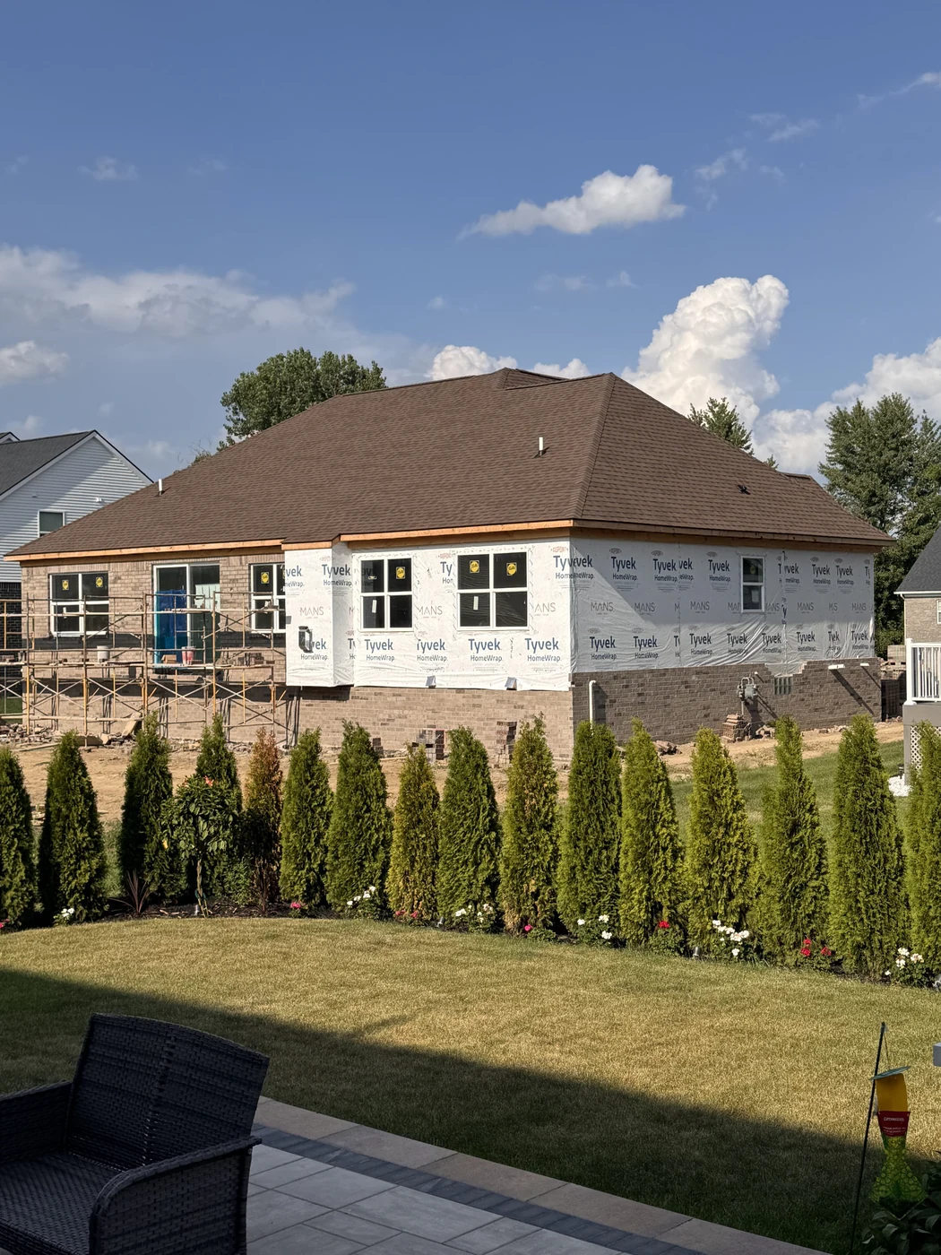 Brick masons installing exterior brick veneer on a new construction home with scaffolding along the walls
