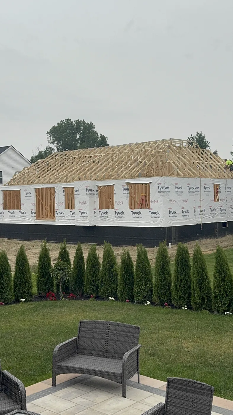 Roof trusses and wood wall framing rising on a new construction home during the structural framing phase