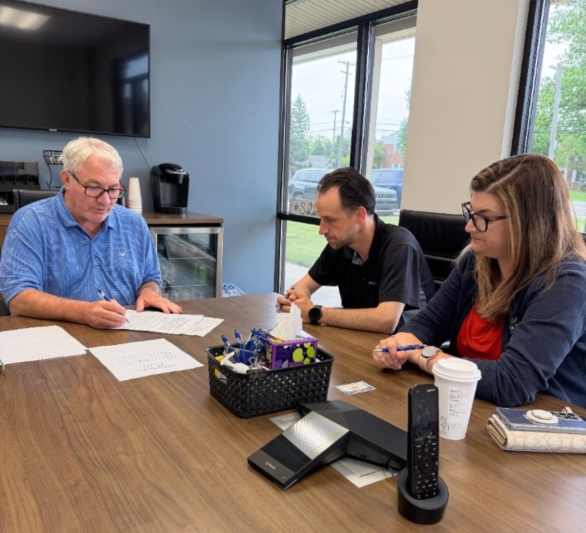 Hearts to Homes clients signing Michigan closing documents with their agent at a title company conference table