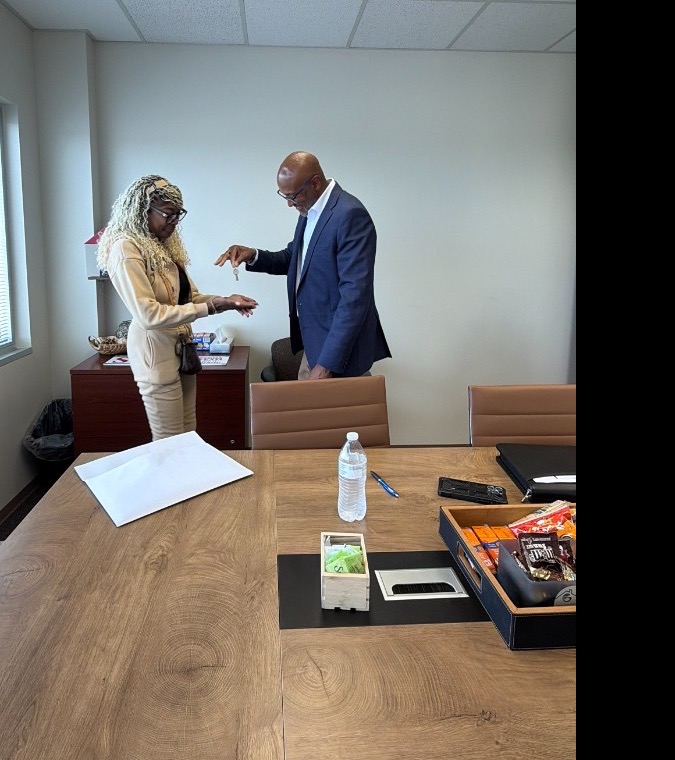 Hearts to Homes Associate Broker handing house keys to a first-time home buyer at a Michigan real estate closing
