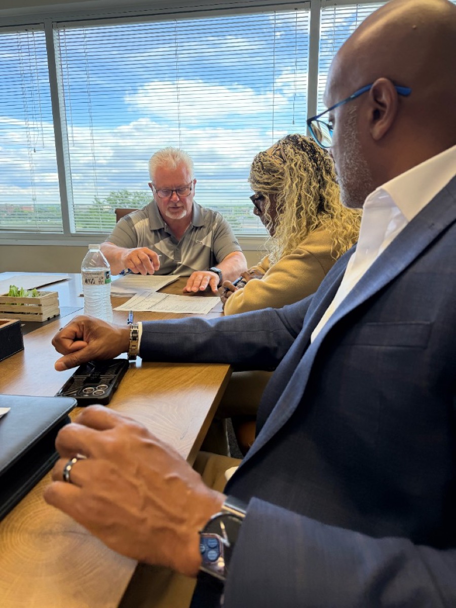 Hearts to Homes team reviewing Michigan closing documents and loan paperwork with first-time home buyers at a conference table