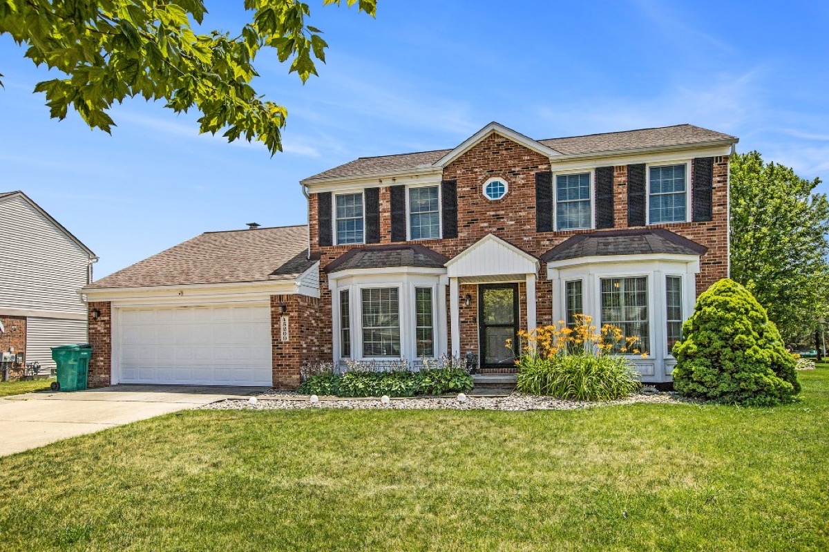 Classic brick colonial home with landscaped yard in a Southeast Michigan neighborhood, representative of resale housing stock in Wayne and Oakland counties