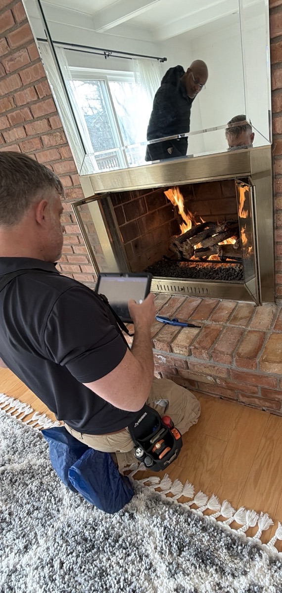 Home inspector examining a fireplace and chimney opening during a Southeast Michigan home inspection