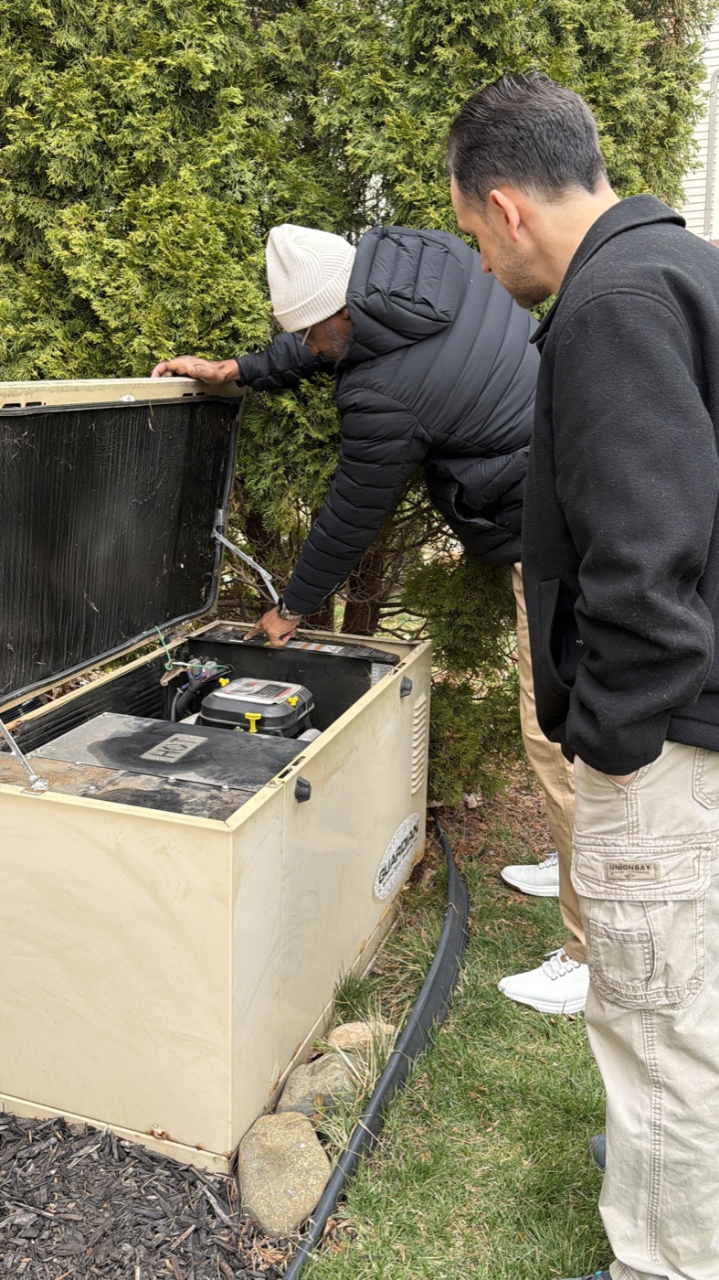 Hearts to Homes team member and home buyer reviewing a whole-home generator during a Southeast Michigan property inspection